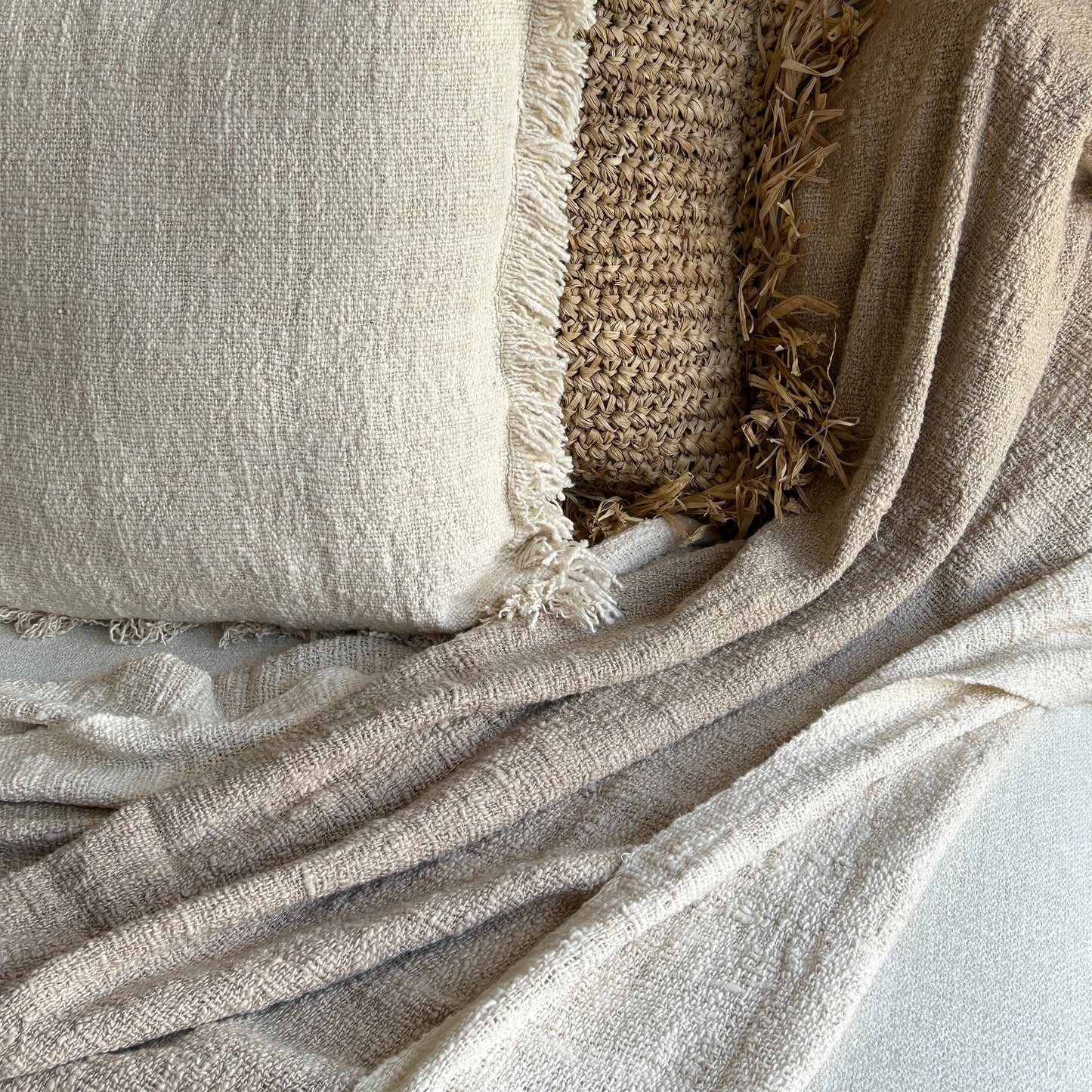 Textured throw shown styled with neutral cushion in same cotton fabric and raffia cushion to add contrast of colour and texture.