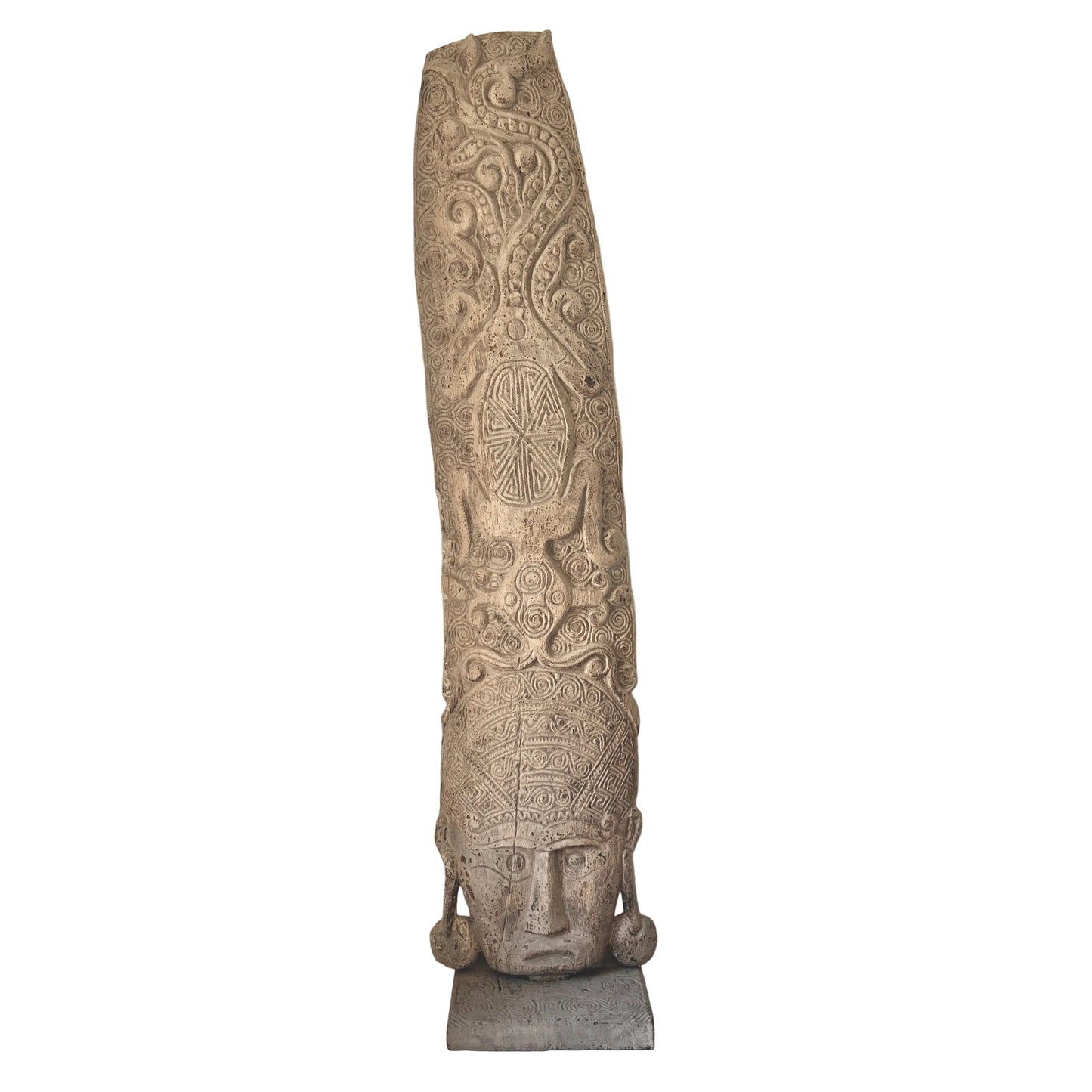 A tall, slender hand-carved wooden sculpture with intricate spiral relief patterns and a pale, stone-like wash finish, standing on a grey rectangular base.