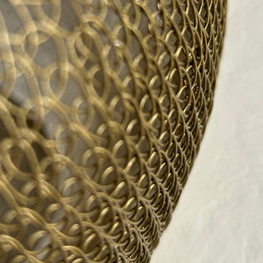 Intricate detail of hand-crocheted gold metal wire mesh showing the delicate looped chainmail technique.