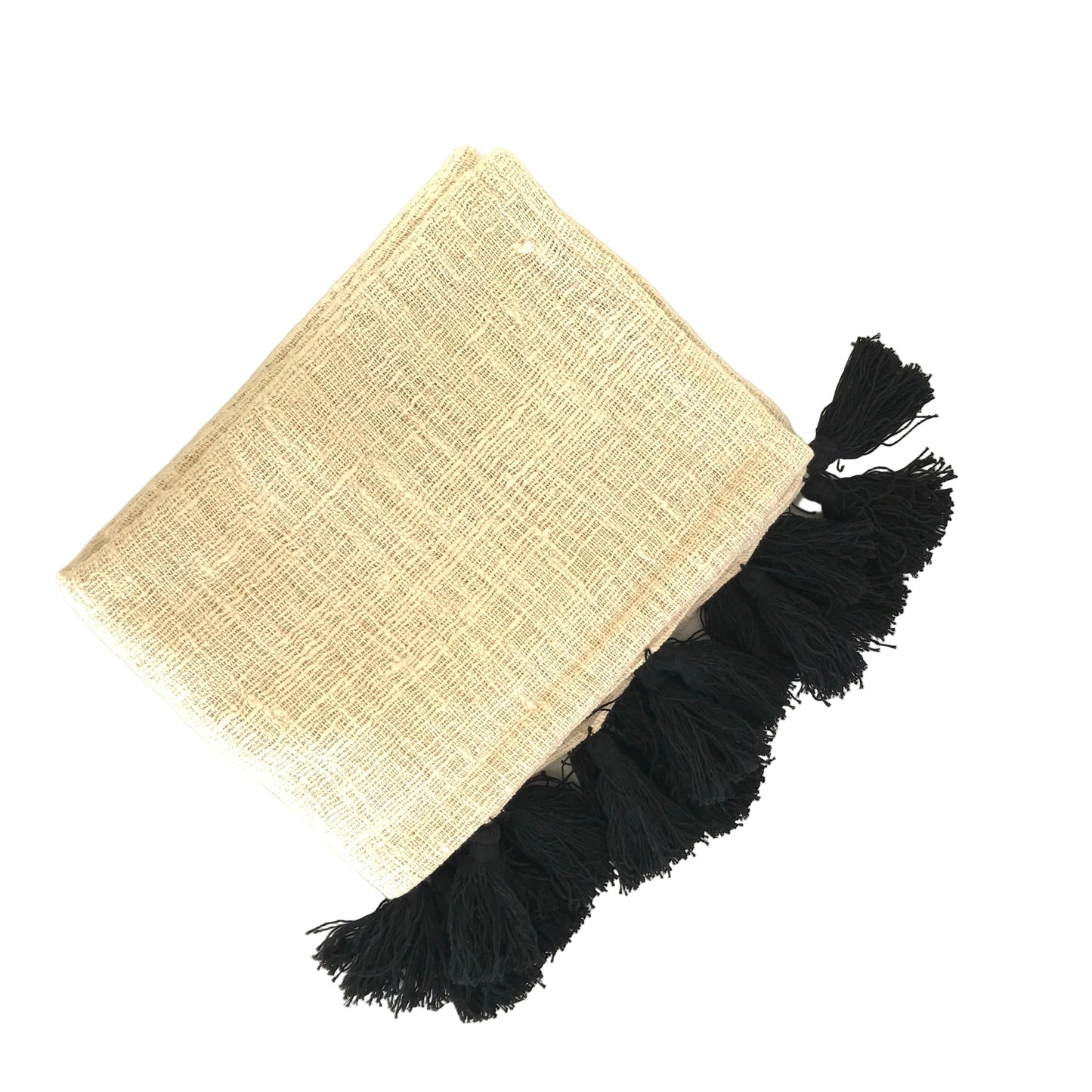 Natural cotton blanket with black tassels folded on a white surface
