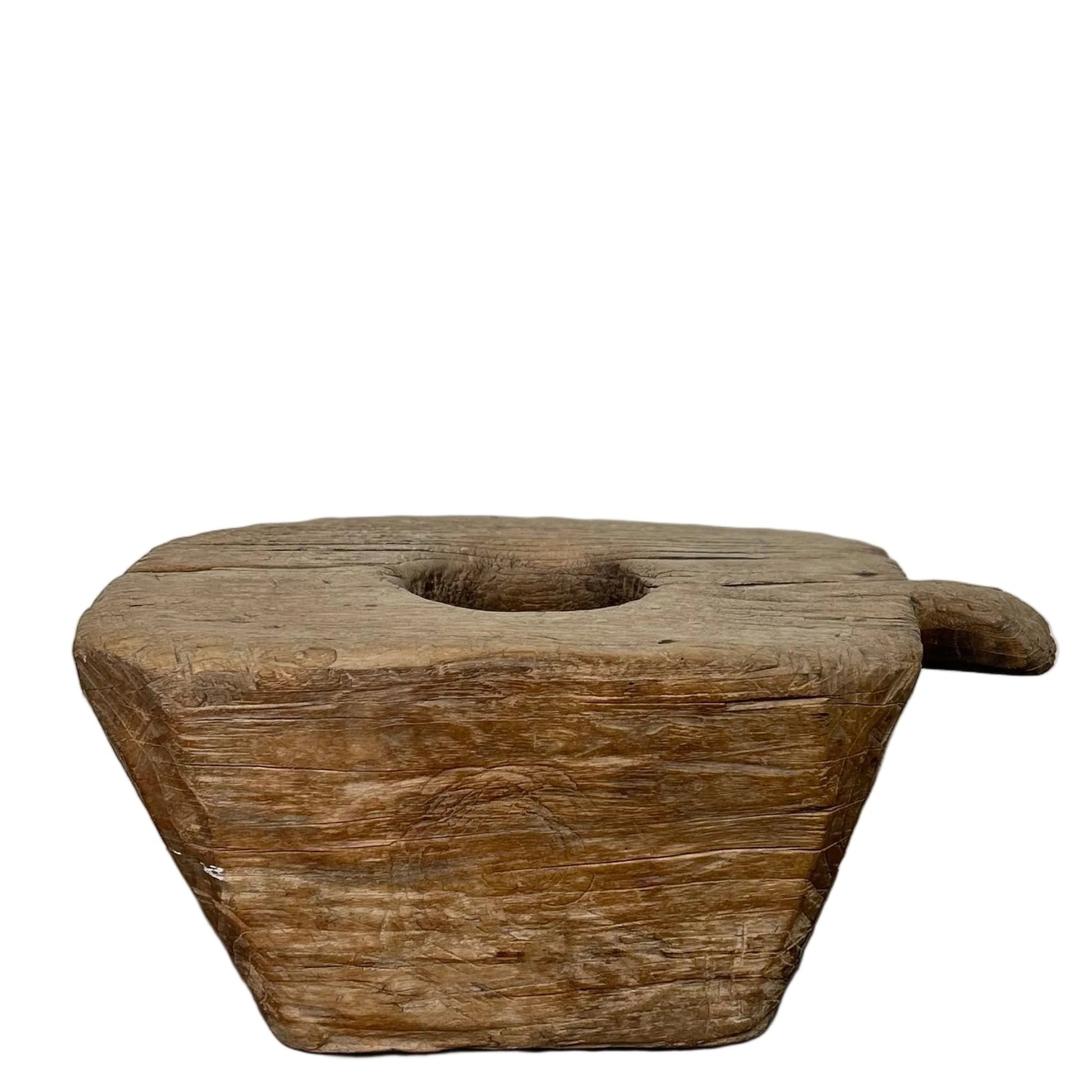 Antique Indonesian teak wood grinder with side handle, central mortar hole, and weathered timber grain on a beige background.