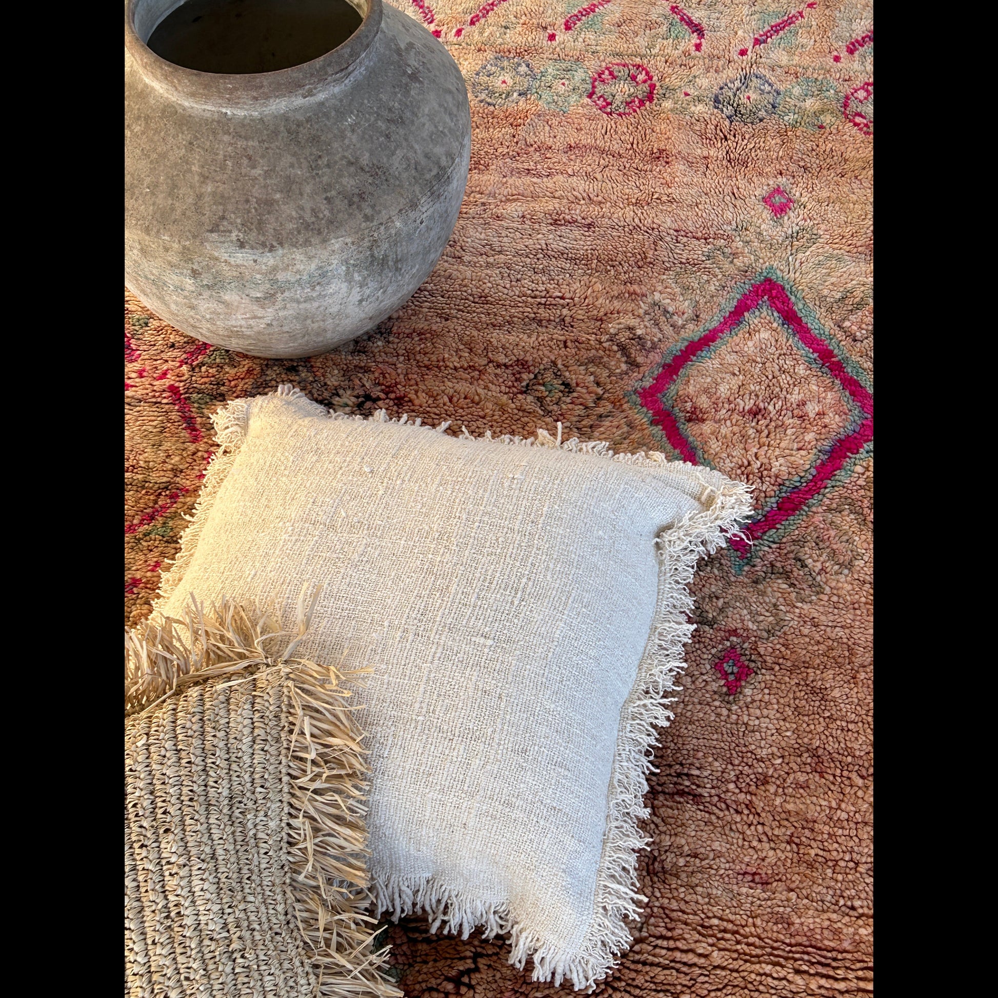 Handmade Moroccan Boujaad rug with a decorative pattern, a raffia and white pillow, and a ceramic pot on a rug surface.