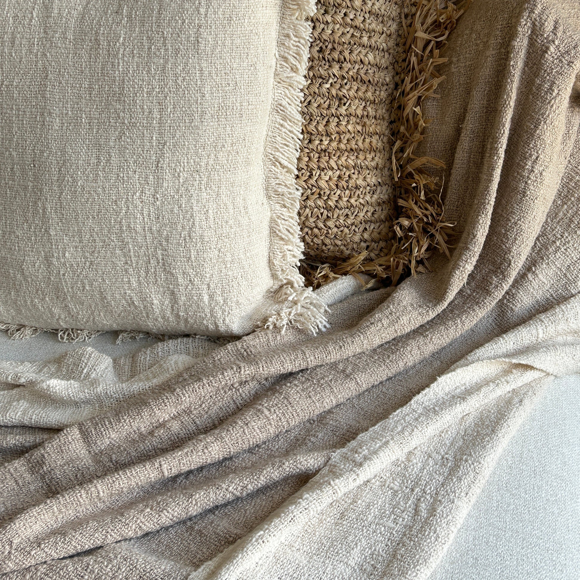 Textured throw shown styled with neutral cushion in same cotton fabric and raffia cushion to add contrast of colour and texture.