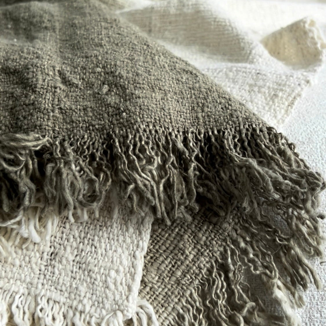 Textured Olive and neutral blanket with fringes draped over a surface