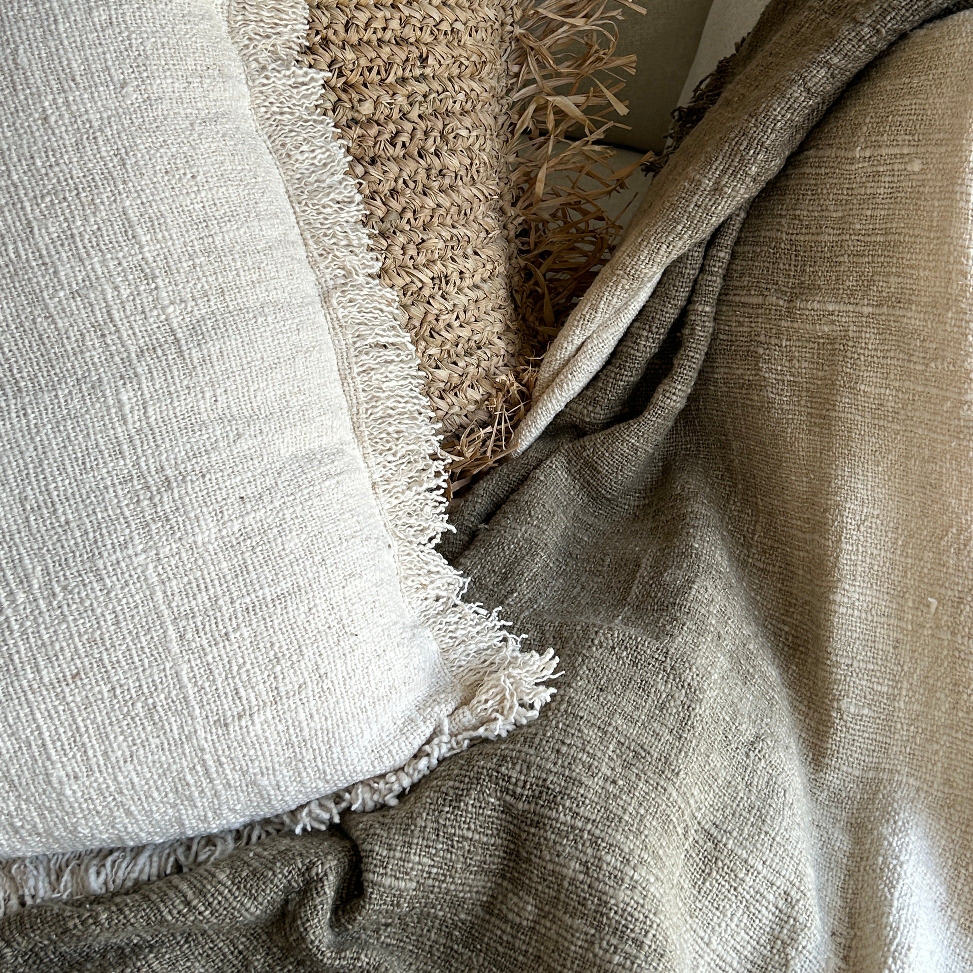 Close up details of Olive throw against a neutral handwoven cushion and raffia cushion