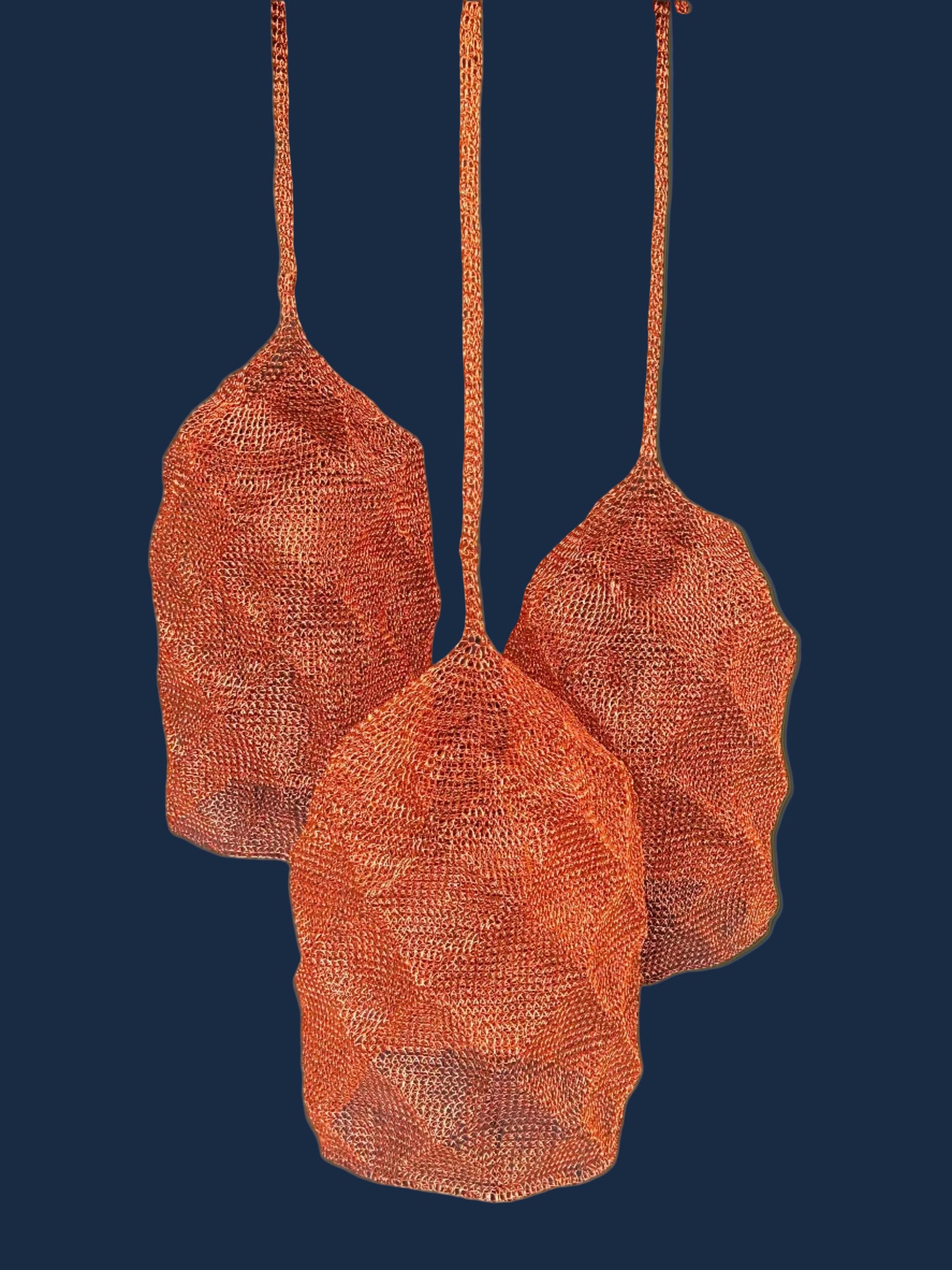Three copper mesh pendant lights hanging against a dark blue background.