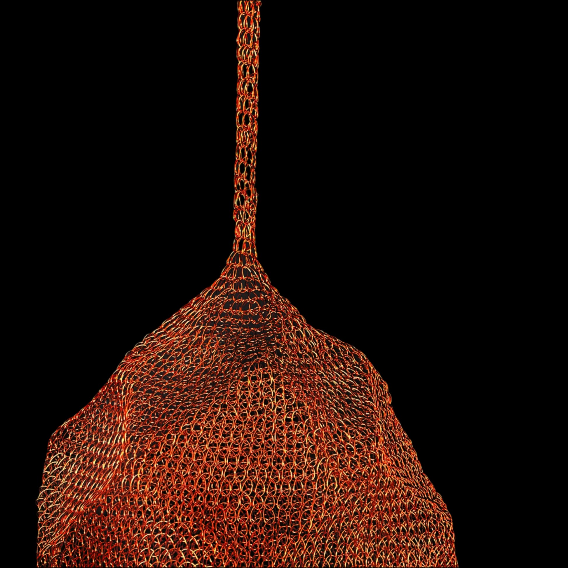 Partial close-up of a woven metal copper coloured mesh pendant shown against a black background.