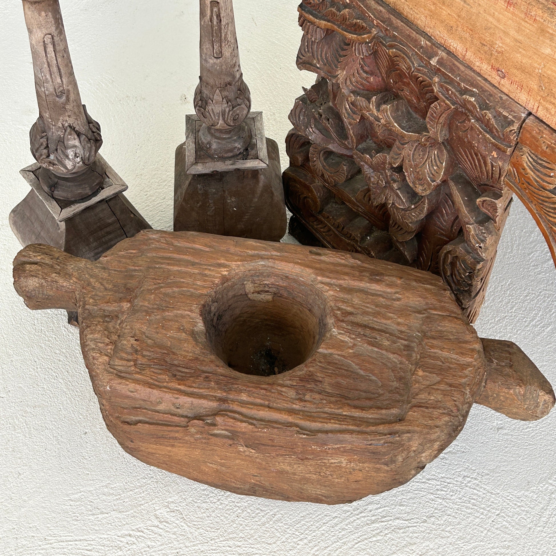 Indonesian Teak wood grinder with two handles, styled against candle holders and coffee table leg.