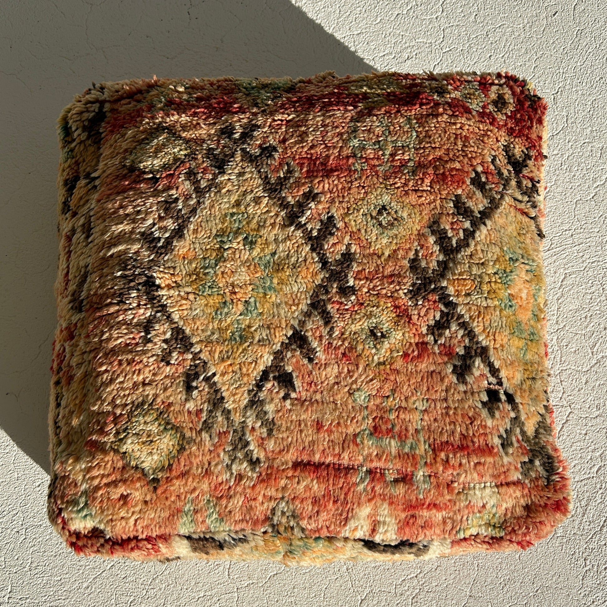Kasbah vintage Moroccan floor cushion featuring terracotta, sage and sand tones with traditional tribal motifs, handcrafted and sourced from Morocco, with afternoon sun shining.