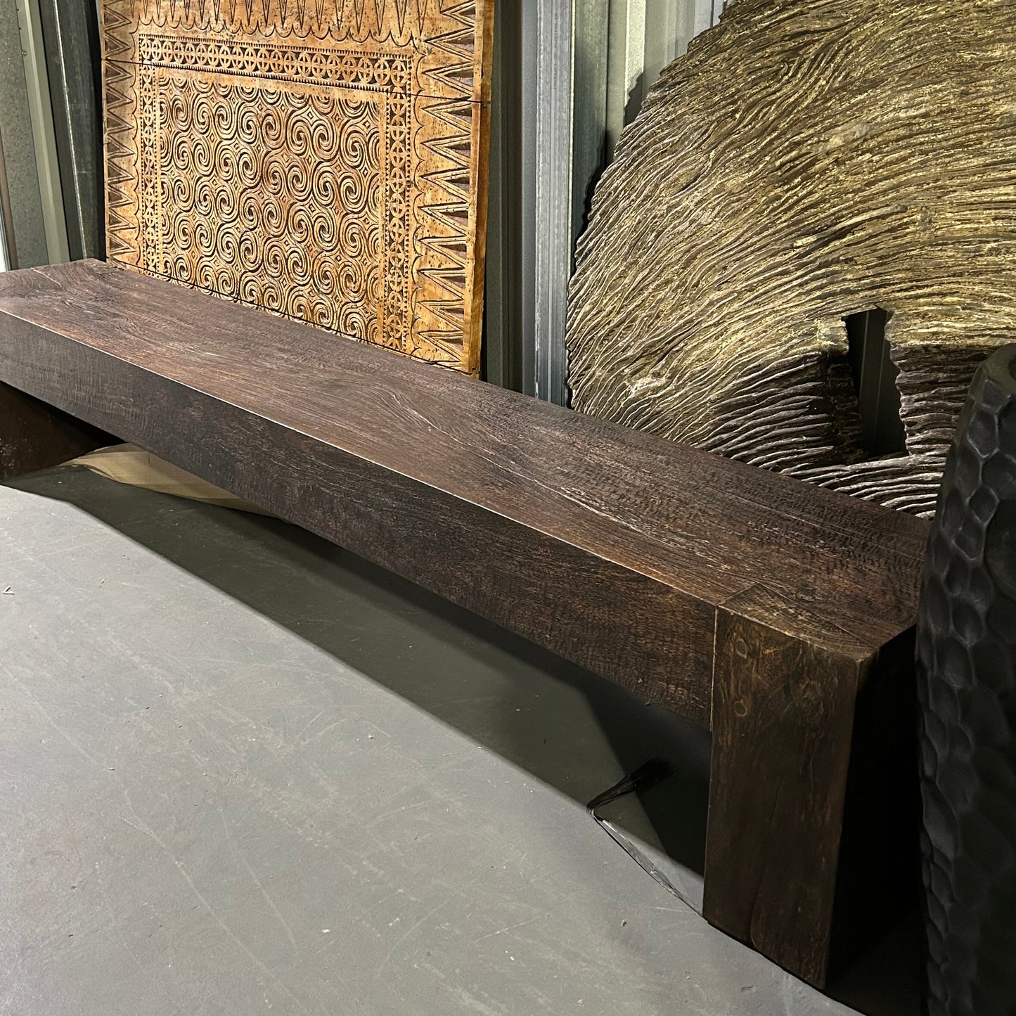 Long brown timber bench seat showing front view at and angle