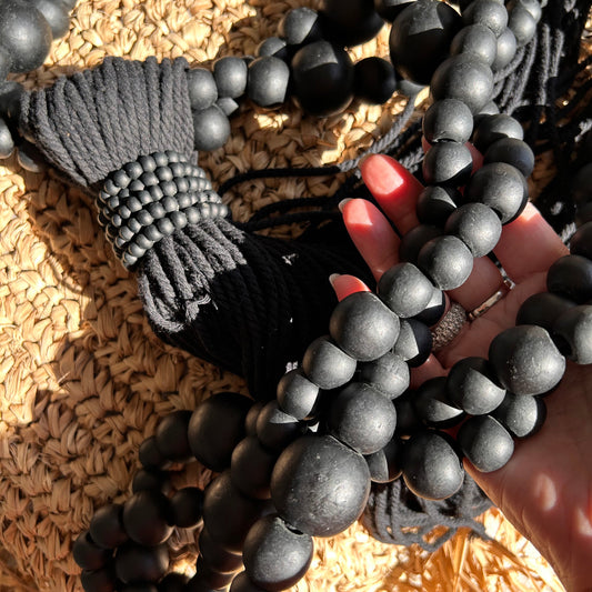 Black beads handheld against a raffia cushion