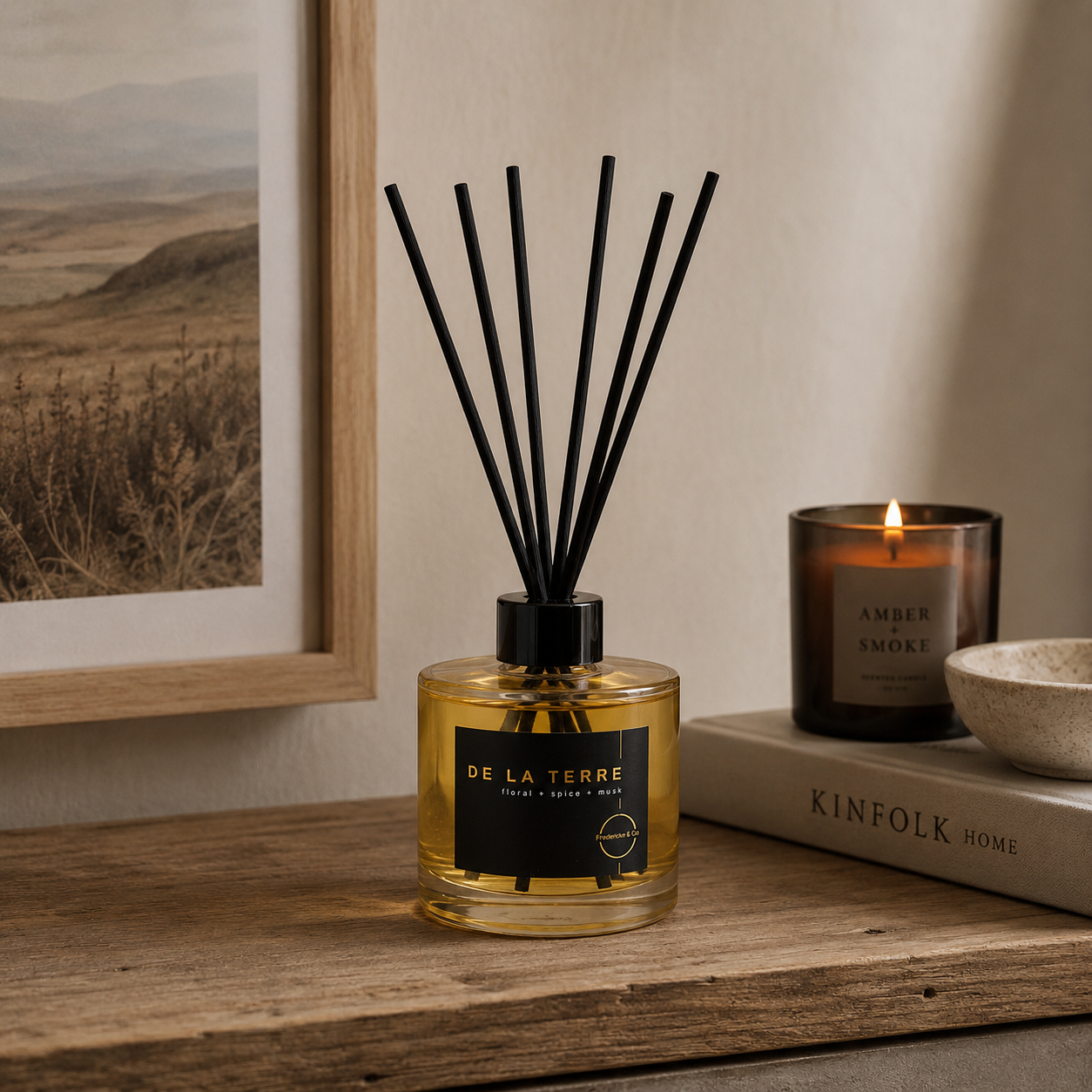 De La Terre diffuser bottle with black reeds, on a timber shelf next to a book, bowl and candle.
