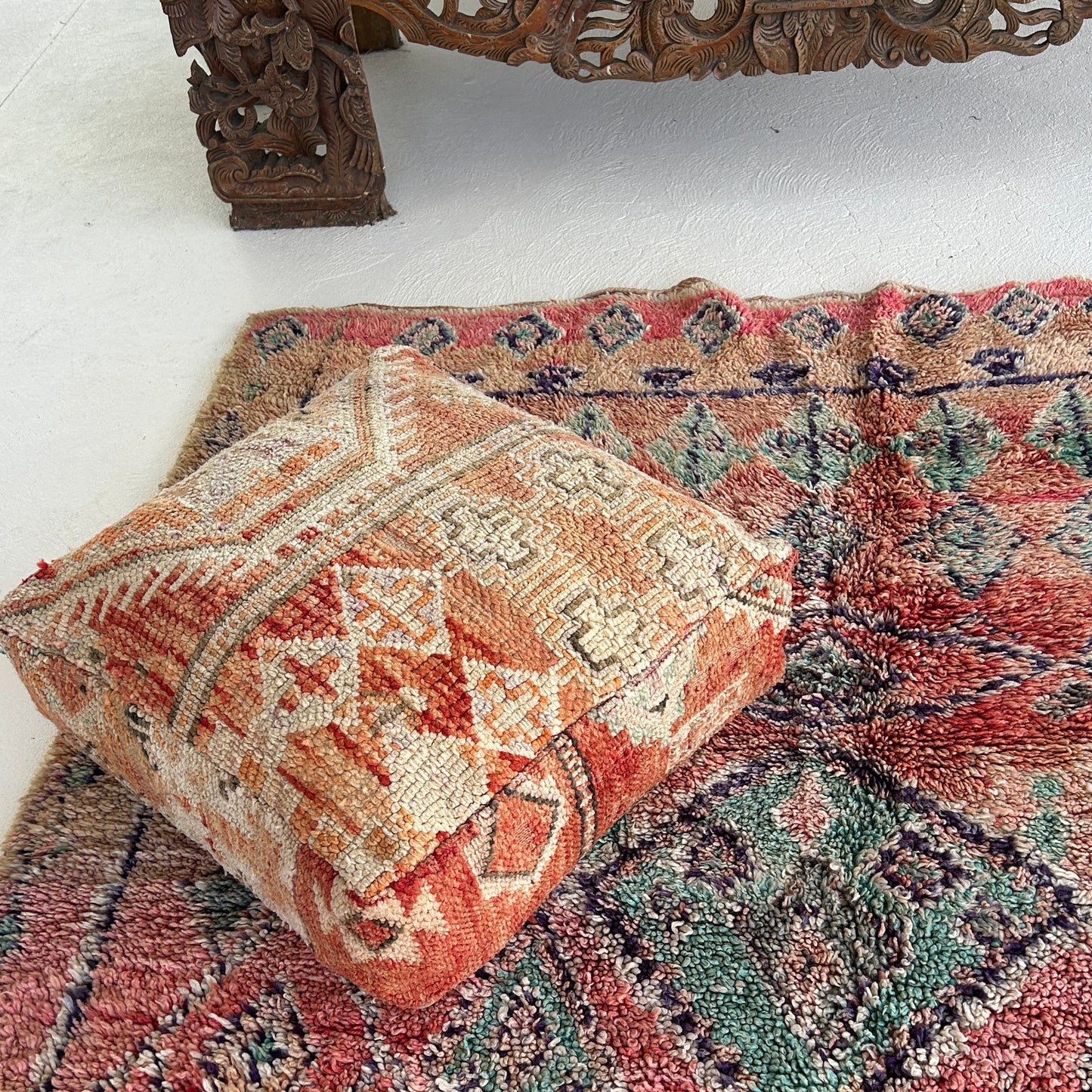Marrakesh vintage Moroccan floor cushion featuring terracotta, cream and sand tones with geometric tribal patterns, on a Moroccan floor rug with colours of raspberry and teal.