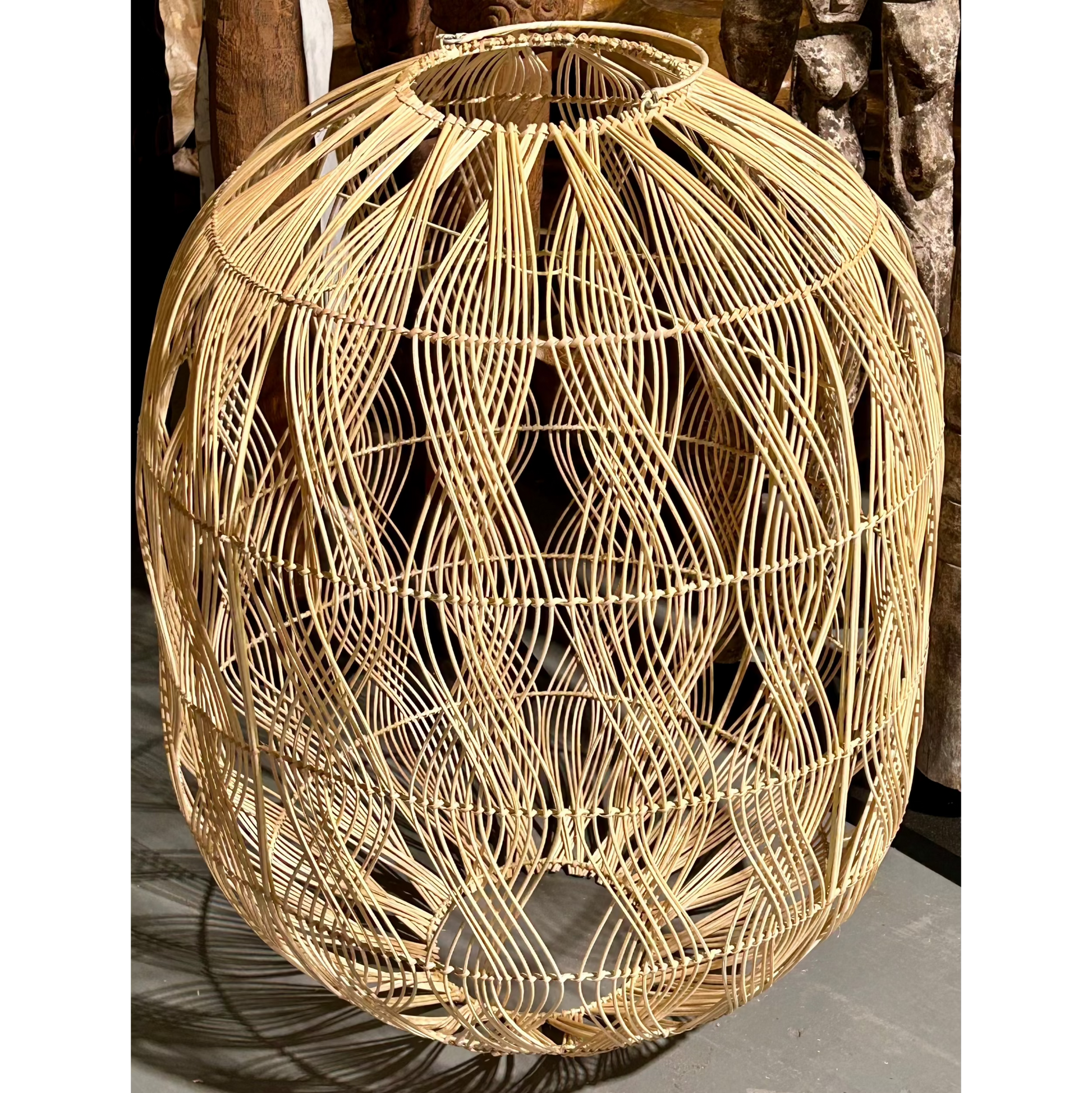 Woven rattan pendant with a vertical wave pattern on a concrete floor.