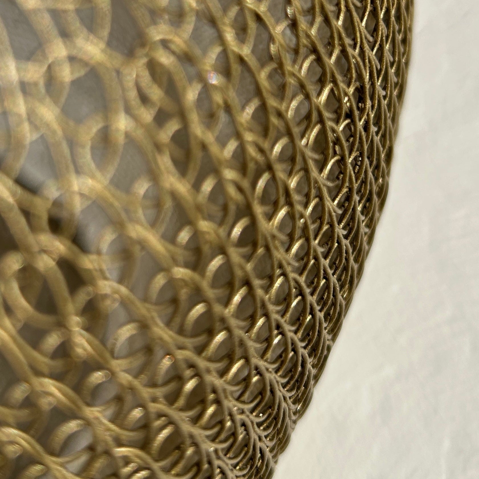 Intricate detail of hand-crocheted gold metal wire mesh showing the delicate looped chainmail technique.