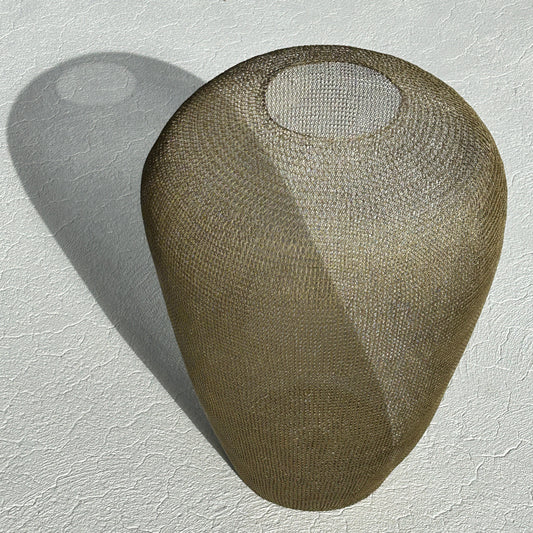 Large 60cm sculptural urn made of hand-crocheted antique gold wire standing on a light-colored tiled floor.