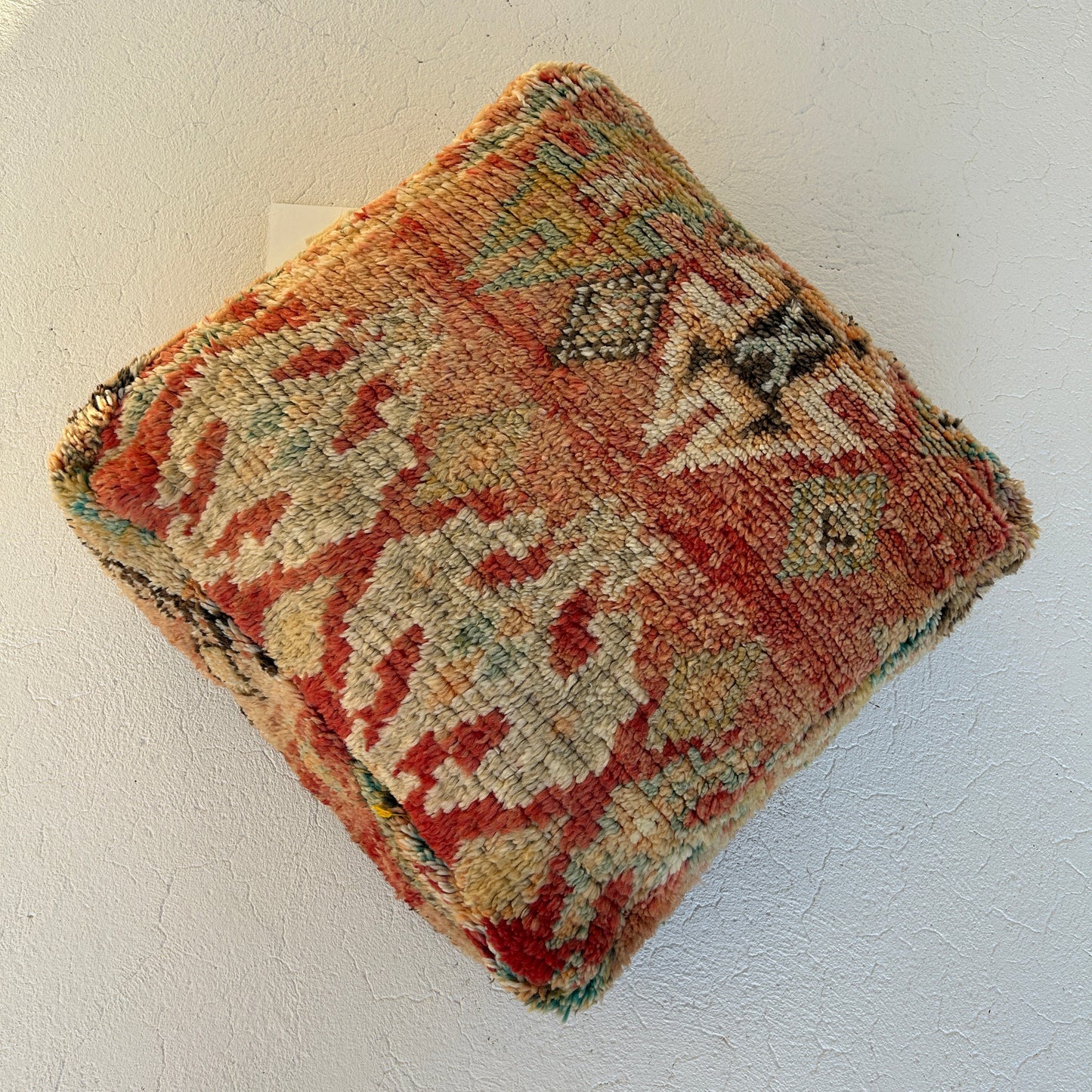 Spice vintage Moroccan floor cushion featuring warm terracotta, saffron and sage tones, handcrafted textile sourced from Morocco, shown against an off white background.
