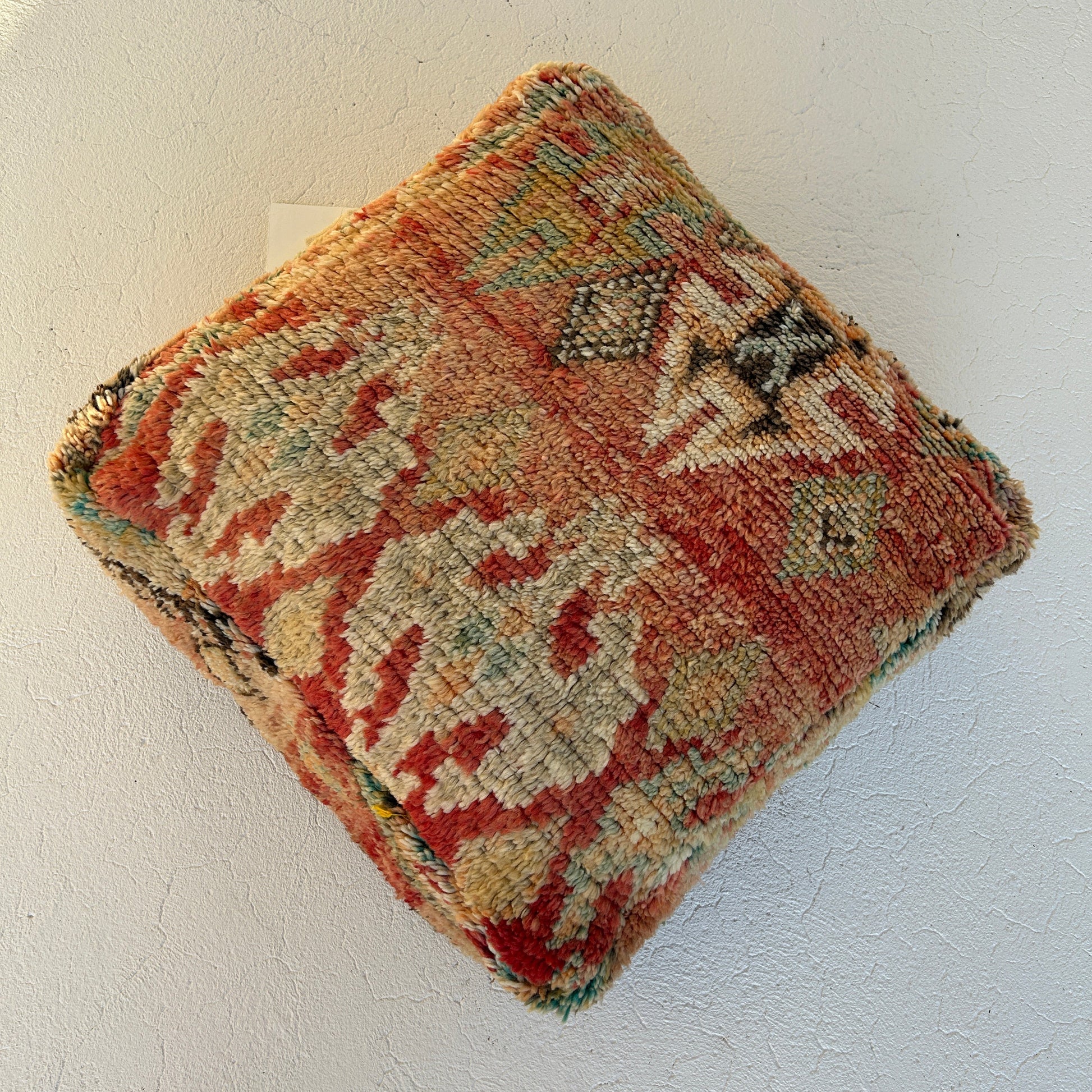 Spice vintage Moroccan floor cushion featuring warm terracotta, saffron and sage tones, handcrafted textile sourced from Morocco, shown against an off white background.