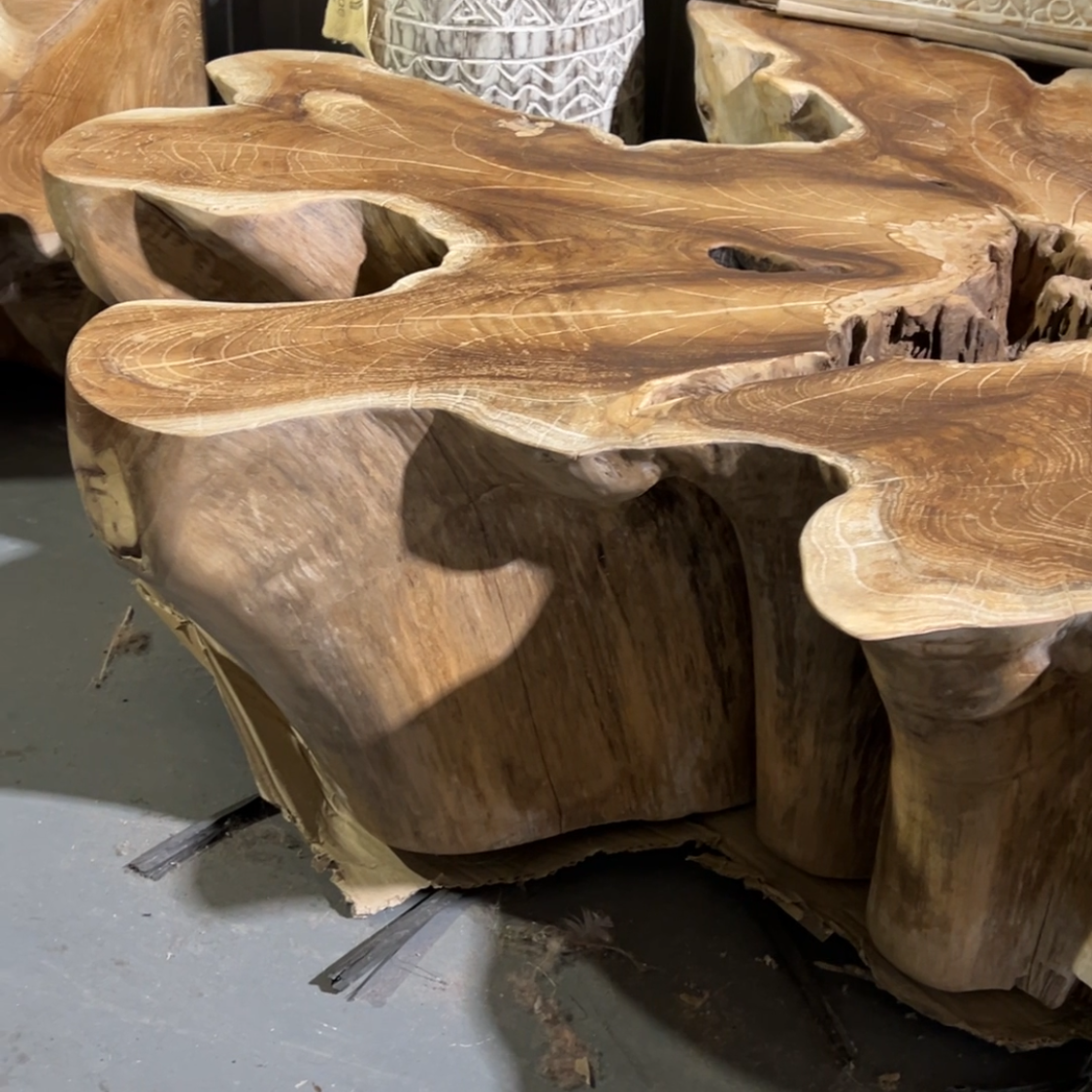 Wooden coffee table with natural, rustic design on a gray floor.