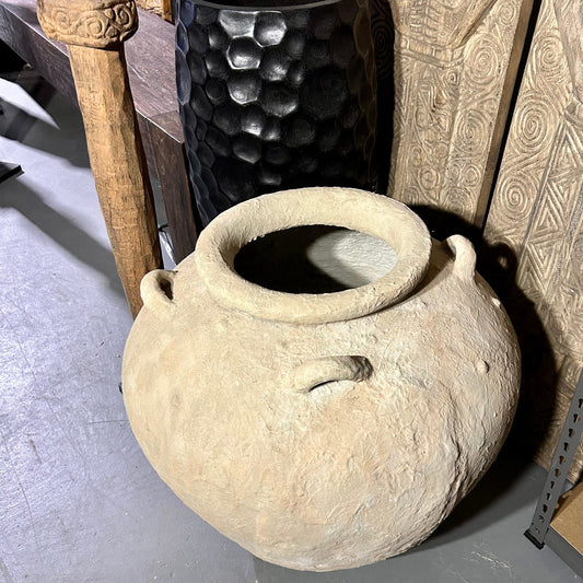 A luxury Artisan Olla vessel crafted from hand-textured fibre cement, showcasing a weathered alabaster finish next to a variety of other interior furnishings