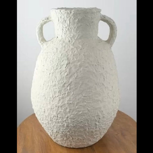 A heavily textured white Indonesian amphora pot with two handles and a distressed, hand-applied finish, displayed on a wooden surface.