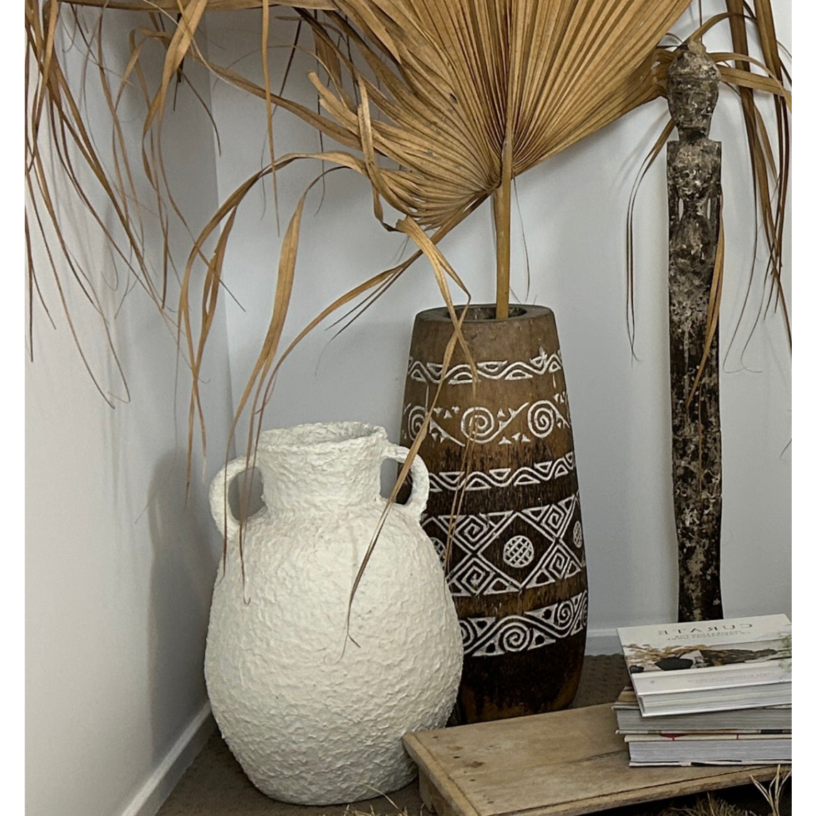 Decorative white Flores Amphora urn shown with dark brown patterned pot with palm leaf and statue.