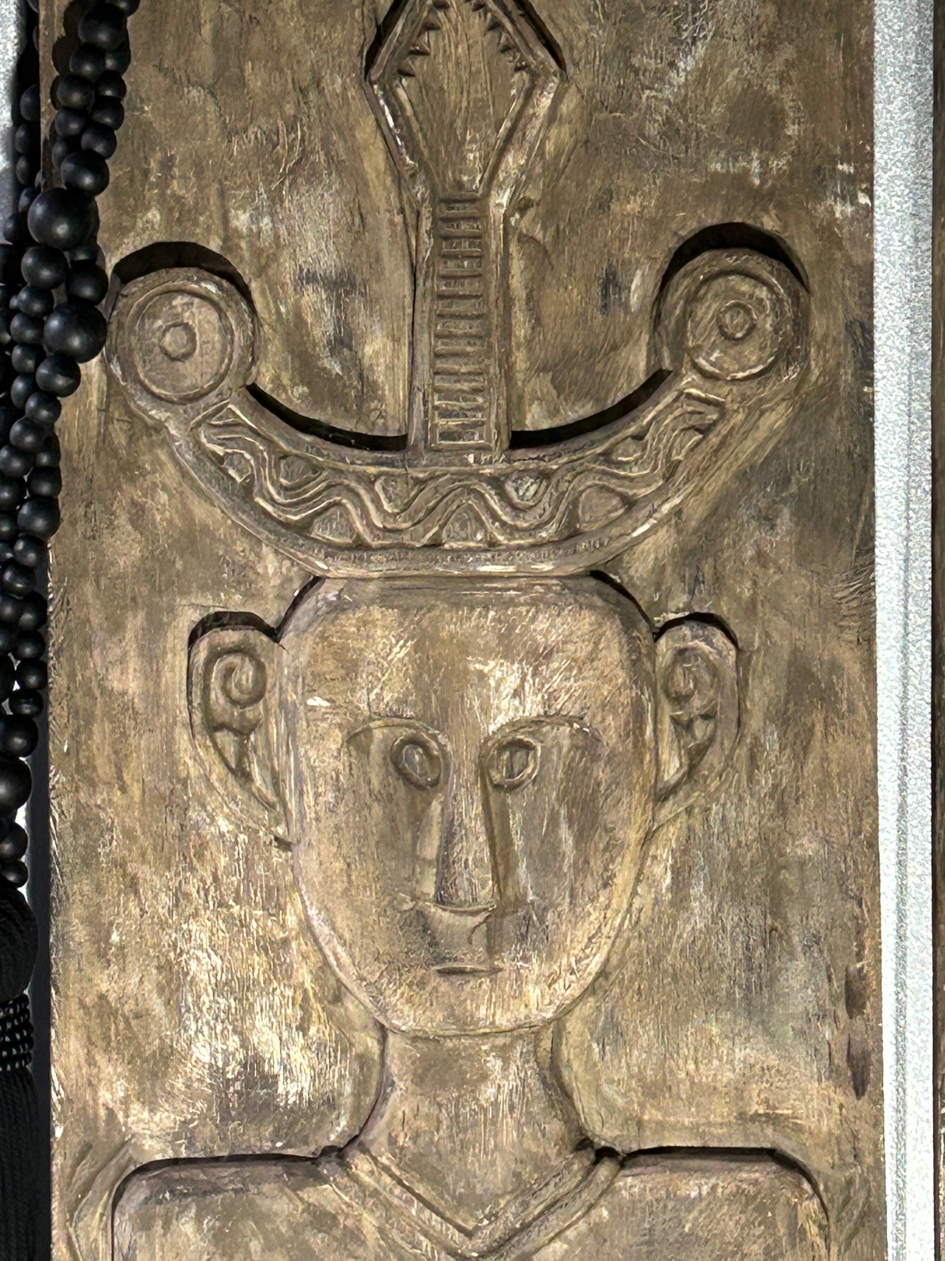 Close up of the face of a hand-carved timber tribal wall panel, known as The Kinship Panels.