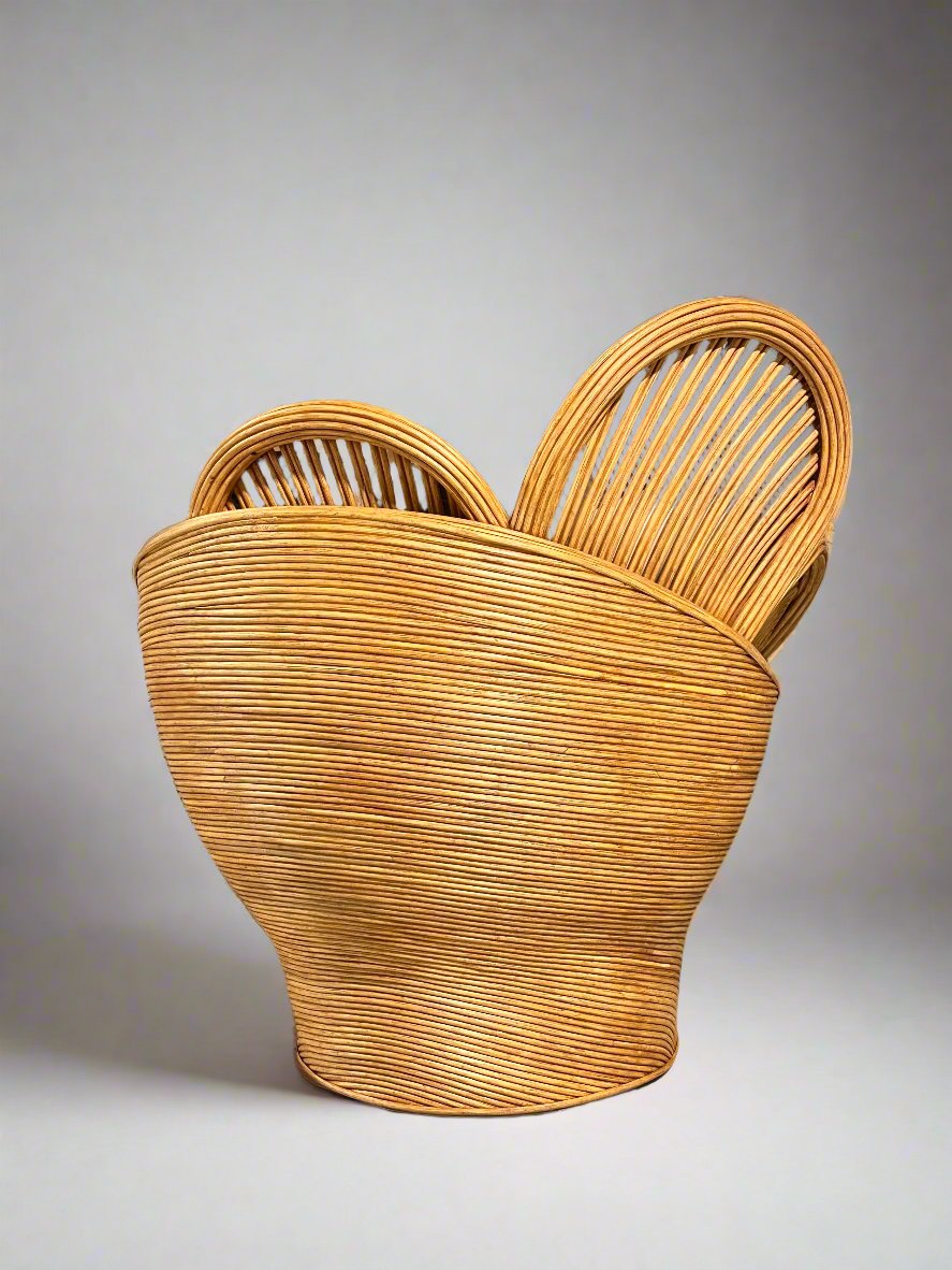 Back view of a round, woven rattan chair against a grey background.