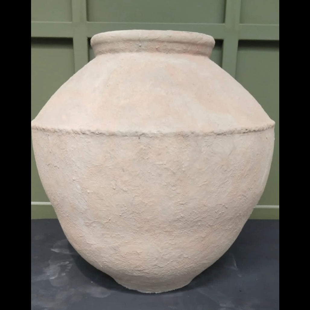 A striking, hand-textured fibre-cement vessel named the 'Petra Vessel,' featuring a sun-bleached sandstone patina and a distinctive architectural mid-band, displayed against a sage-green panelled backdrop.