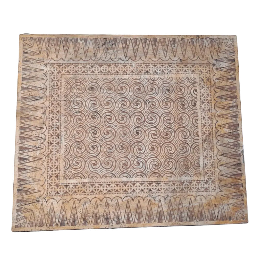 Large hand-carved wooden Toraja panel featuring traditional Sulawesi spiral pa'barre allo motifs, zigzag and dot-circle border patterns, natural timber tones, displayed landscape.