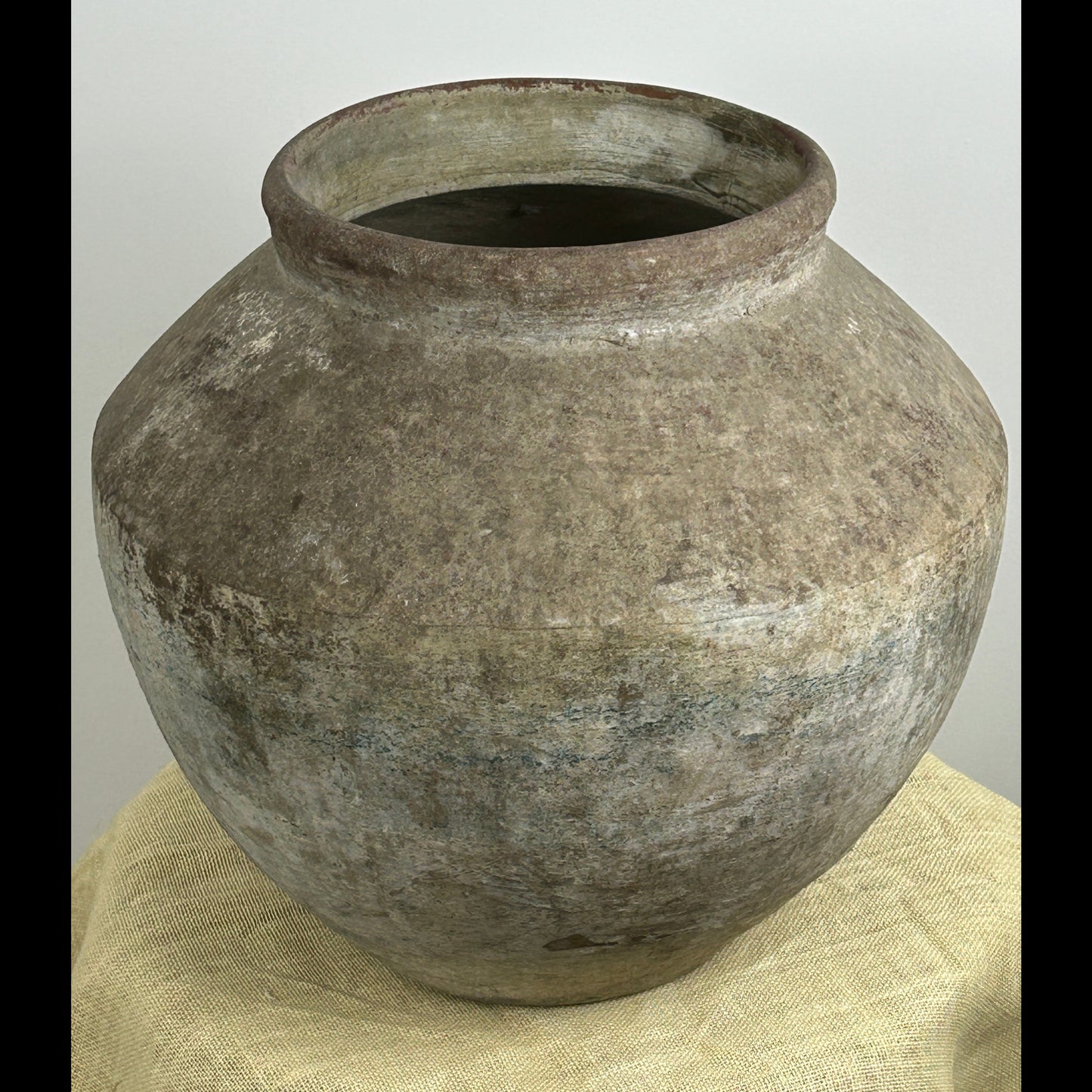 Large rounded urn with a weathered stone-like texture and distressed grey patina made from cement fiber resin.
