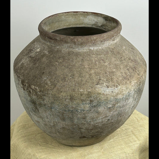 Large rounded urn with a weathered stone-like texture and distressed grey patina made from cement fiber resin.