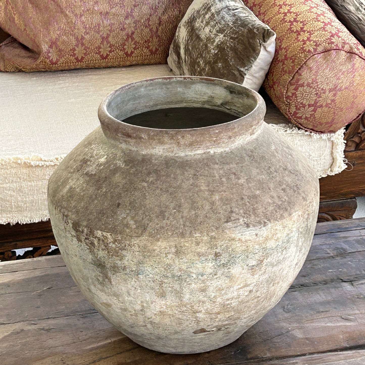 Weathered urn on an old wooden coffee table on a patio.