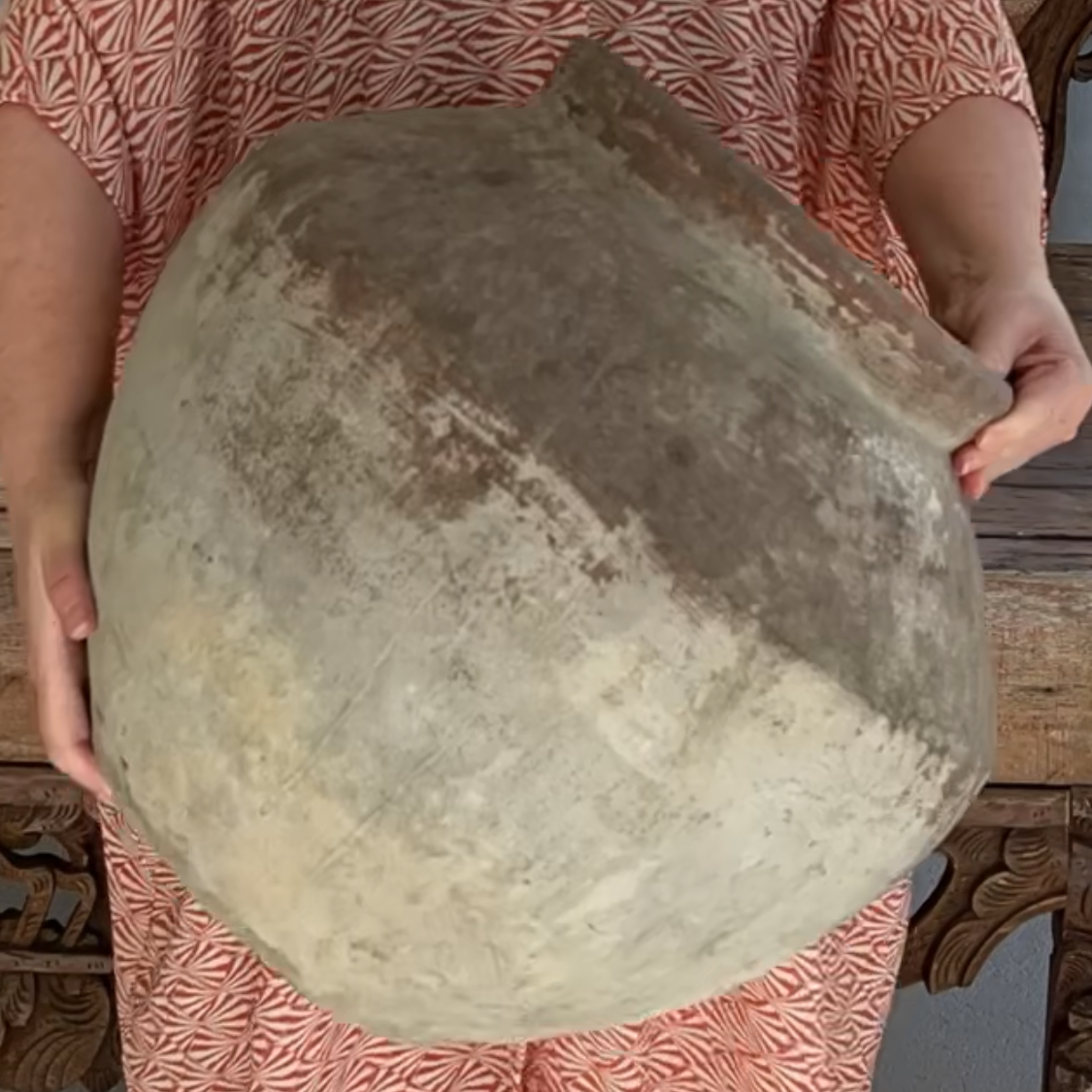 Person holding a weathered urn.