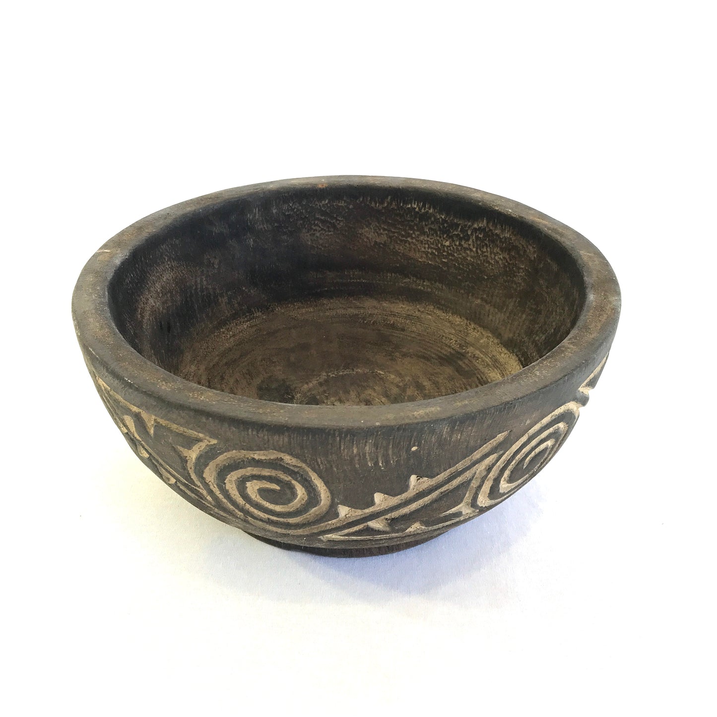 A small decorative carved Indonesian timber bowl in black and brown colors, with visible swirling patterns on the side.