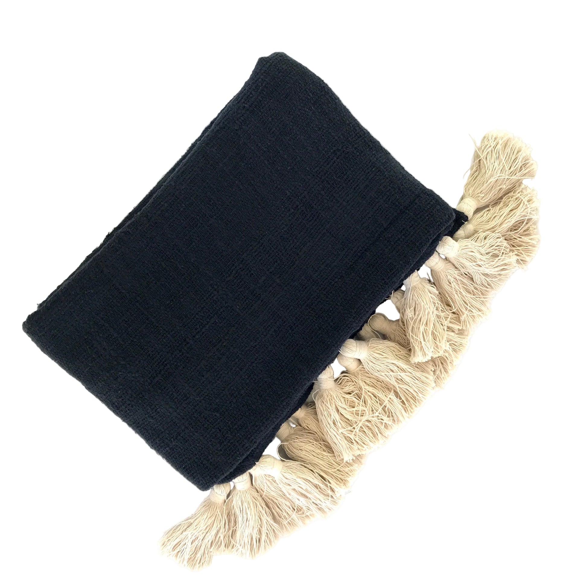 Black cotton blanket with natural tassels folded on a white surface