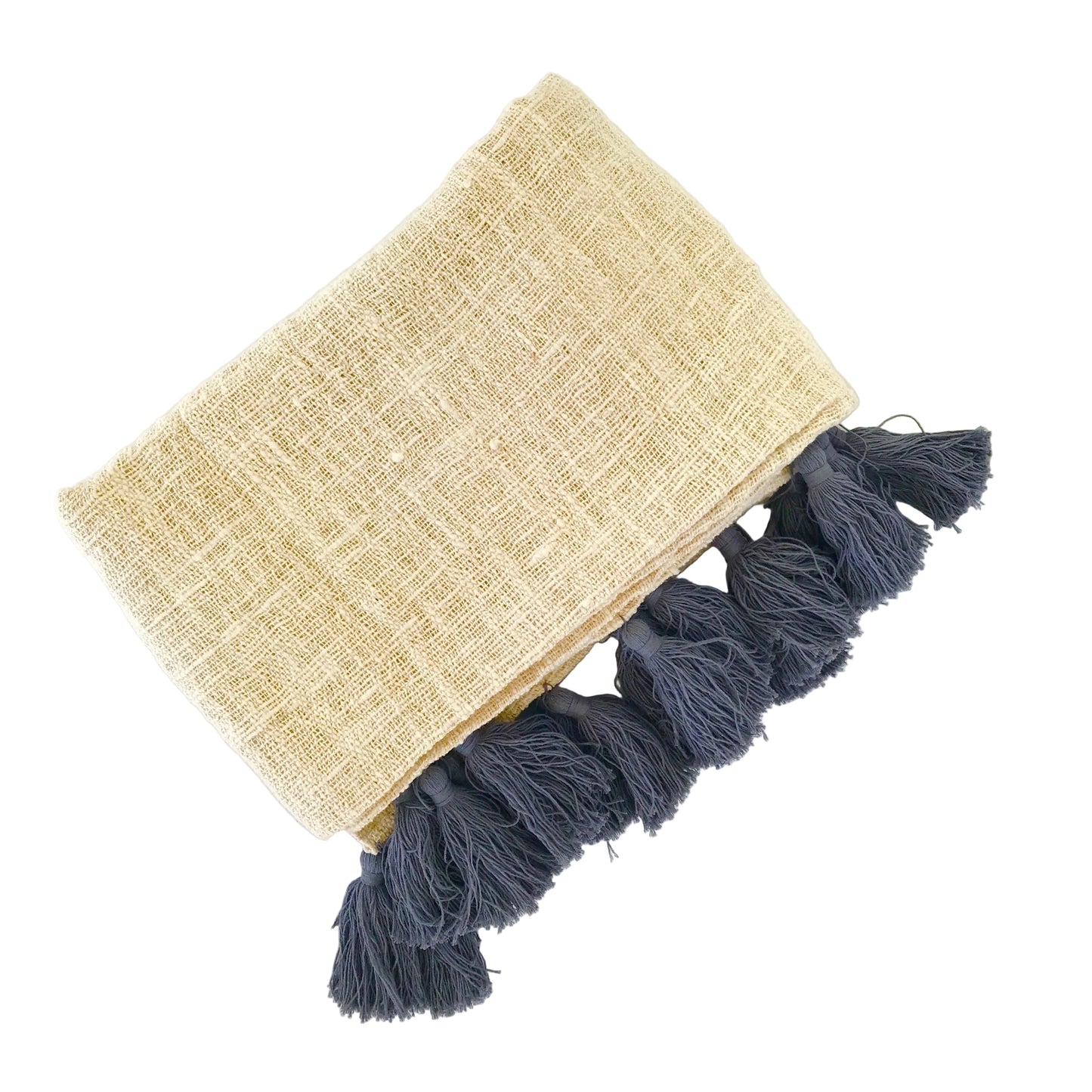 Natural cotton blanket with grey tassels folded on a white surface