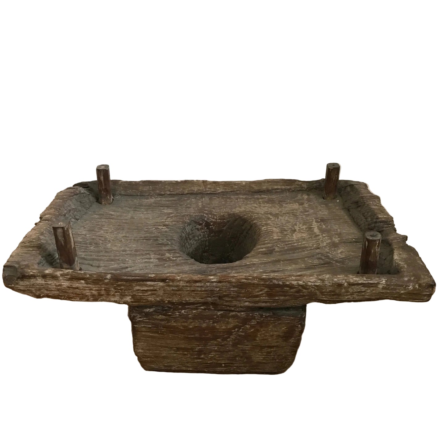 Authentic vintage Indonesian hand-carved wooden spice grinder with four corner pegs and a central basin on a timber floor.