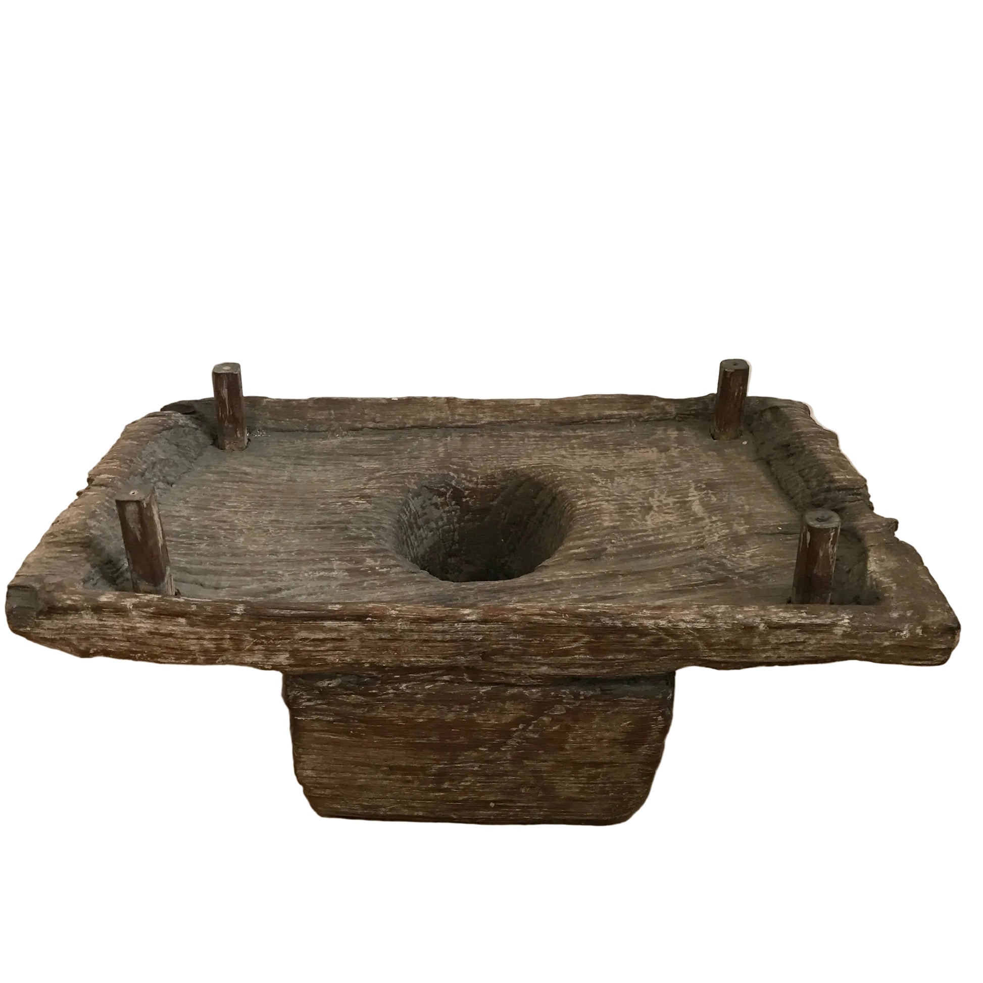 Authentic vintage Indonesian hand-carved wooden spice grinder with four corner pegs and a central basin on a timber floor.